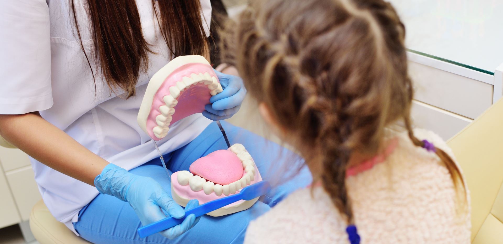 Zahnärztin erklärt Mädchen worauf es bei Zahnvorsorge ankommt