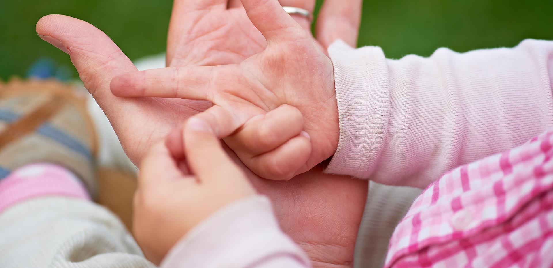 Erwachsenenhand und Kinderhand liegen ineinander, das Kind zählt mit den Fingern