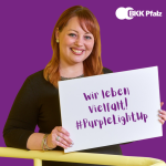 Mitarbeiterin der BKK Pfalz hält Schild mit der Aufschrift "Wir leben Vielfalt"
