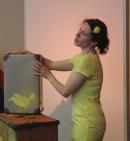 Kindertheater: Frau in gelbem Kleid mit gelbem Koffer