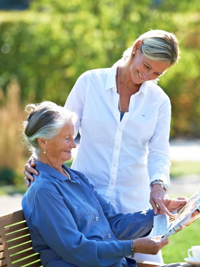 Pflegekraft unterhält sich mit älterer Frau