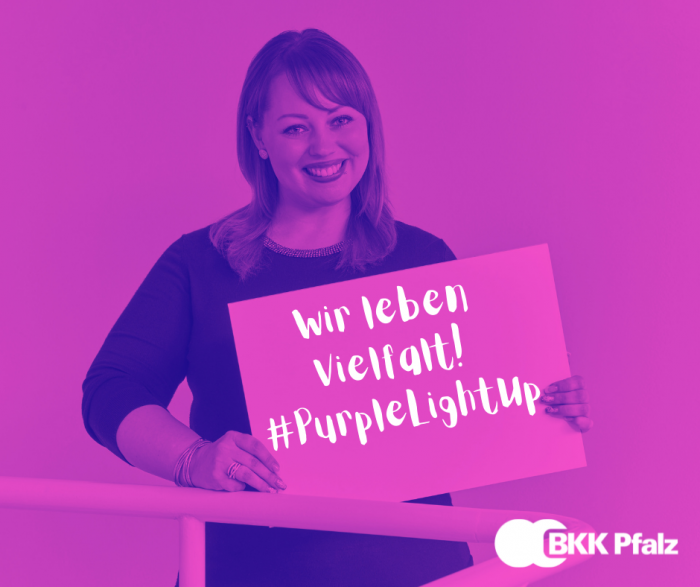 Mitarbeiterin der BKK Pfalz hält Schild mit der Aufschrift Wir leben Vielfalt, #PurpleLightUp, Foto ist lila eingefärbt