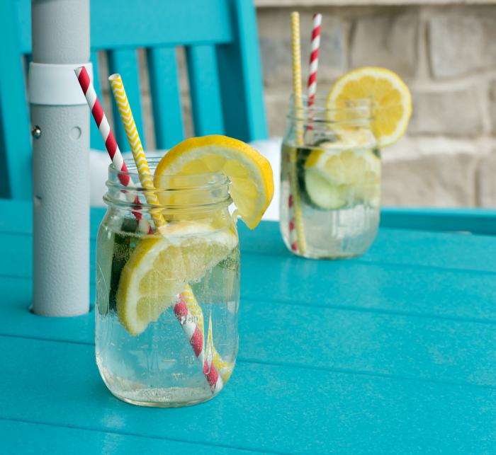 Zwei Gläser mit Wasser und Zitronenscheiben stehen auf einem Gartentisch