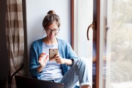 Junge Frau mit Smartphone beim Nutzen digitaler Angebote