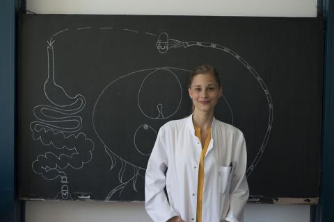 Die Medizinerin Giulia Enders im Kittel in einem Seminarraum vor einer Tafel