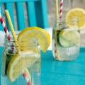 Zwei Gläser mit Wasser und Zitronenscheiben stehen auf einem Gartentisch